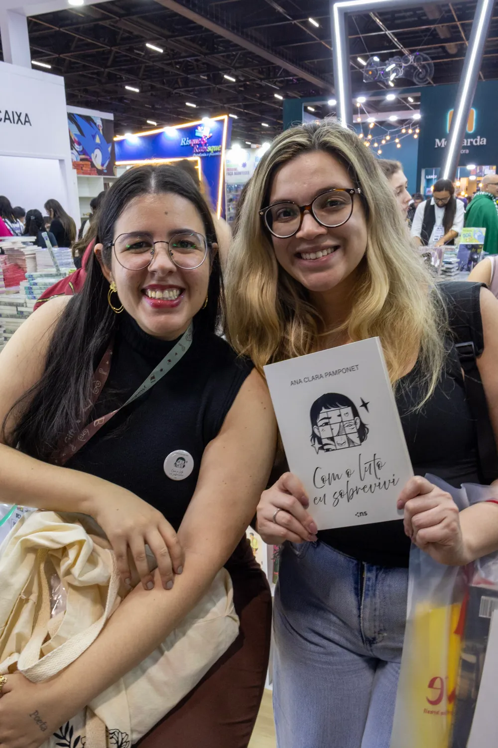 Ana Clara Pamponet com uma leitora segurando o livro Com o luto eu sobrevivi