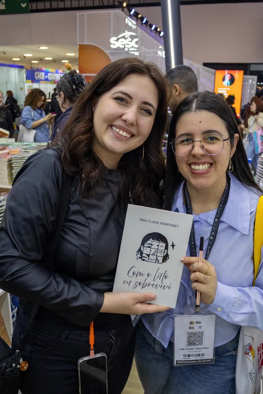 Ana Clara Pamponet com uma leitora exibindo o livro Com o luto eu sobrevivi