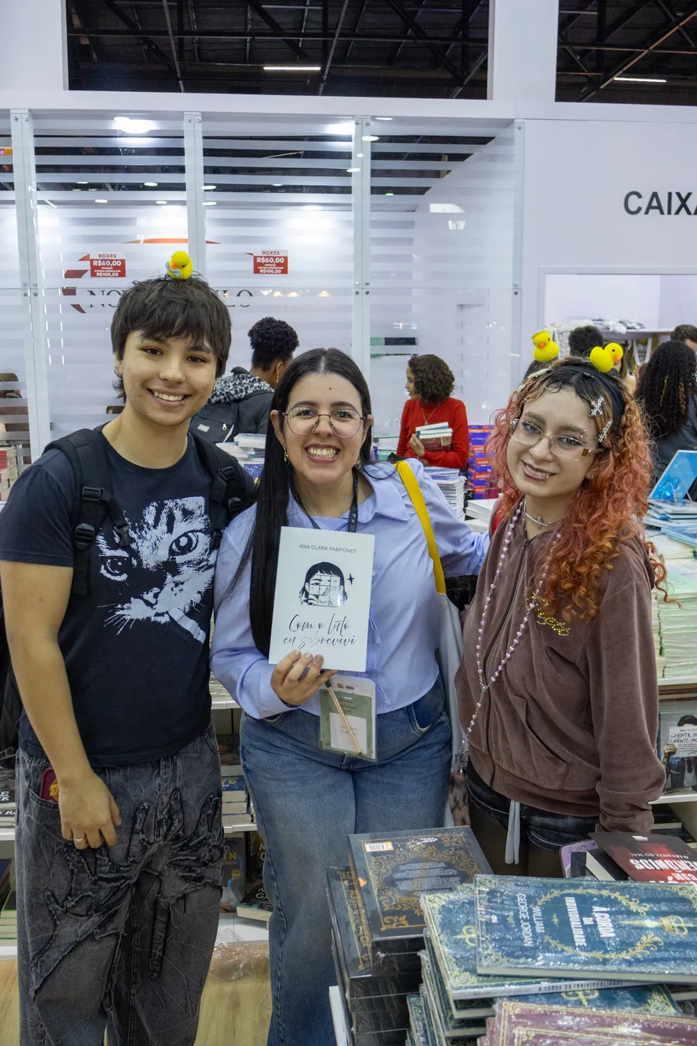 Ana Clara Pamponet com dois visitantes no estande da Bienal